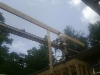 Carpenter setting a ridge beam over a new addition frame — Ice Dam Removal by Roofing Brothers in Nashua